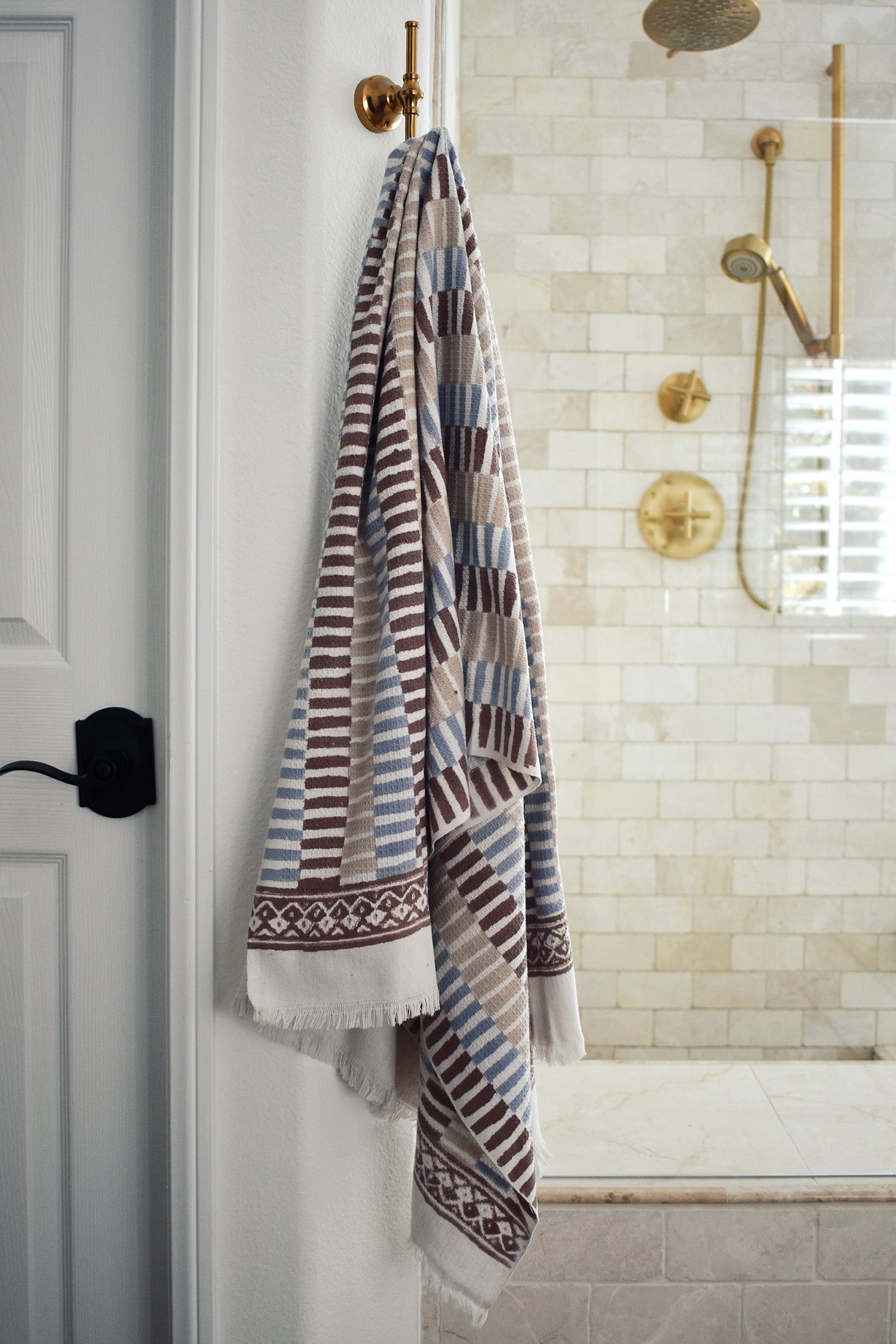 Block printed striped khadi bath towel hanging on a shower hook