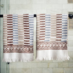 Block printed striped waffle weave khadi hand towels hanging on a shower rod