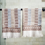 Block printed striped waffle weave khadi hand towels hanging on a shower rod