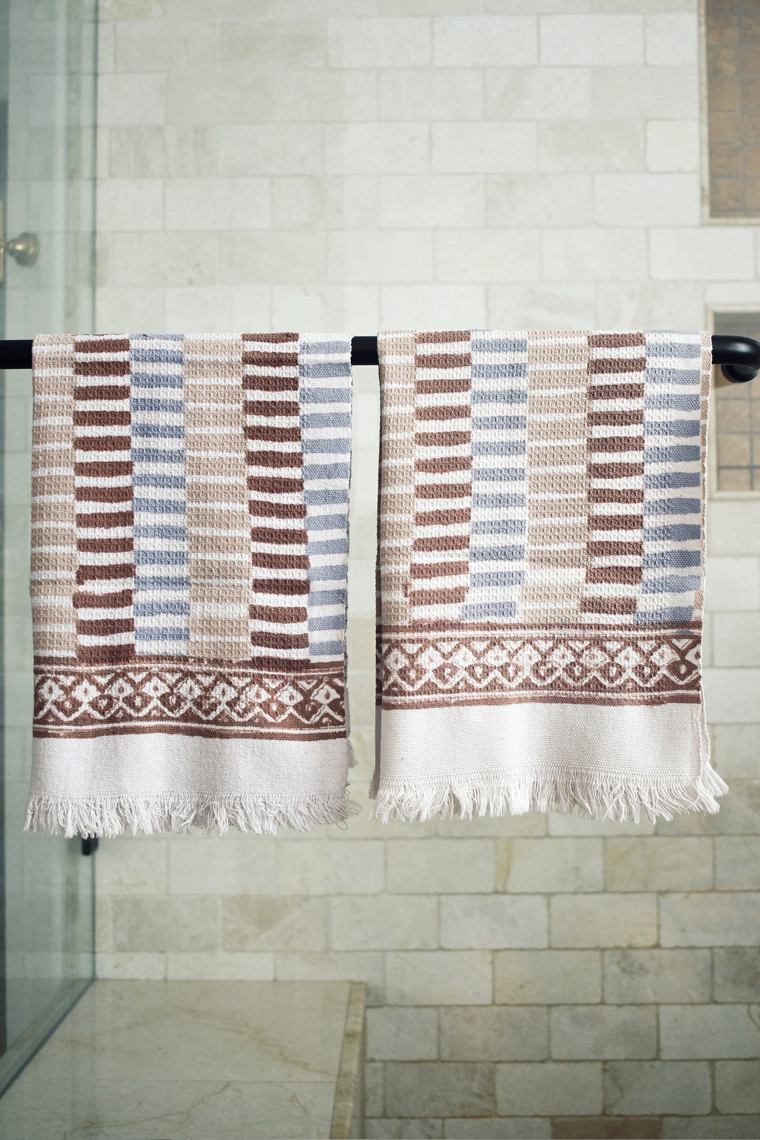 Block printed striped waffle weave khadi hand towels hanging on a shower rod