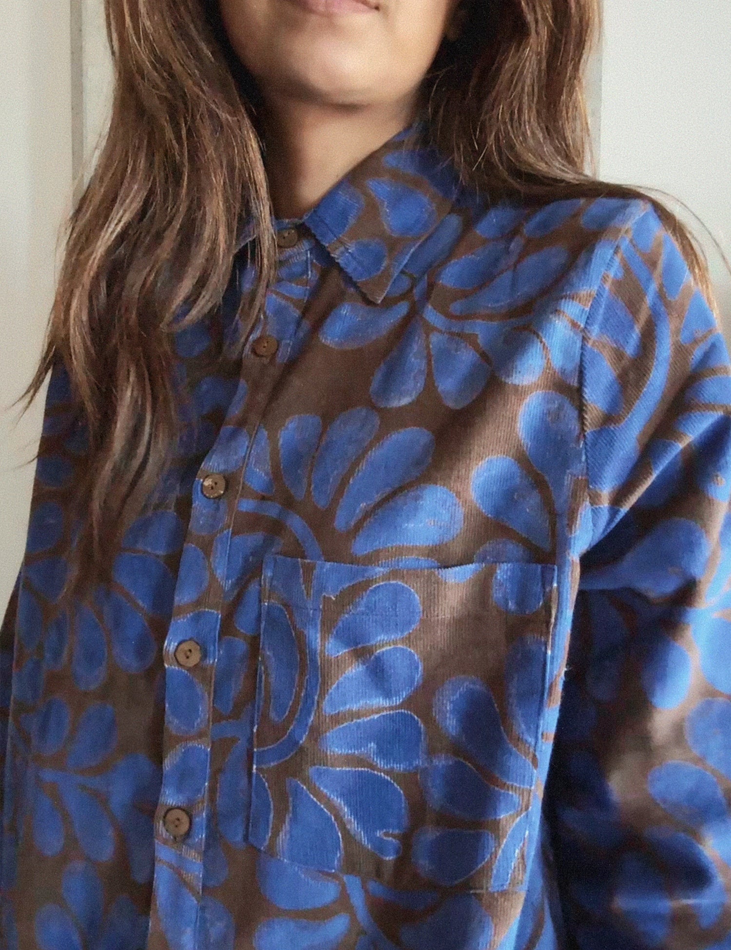 Person wearing a blue and brown floral patterned corduroy shirt