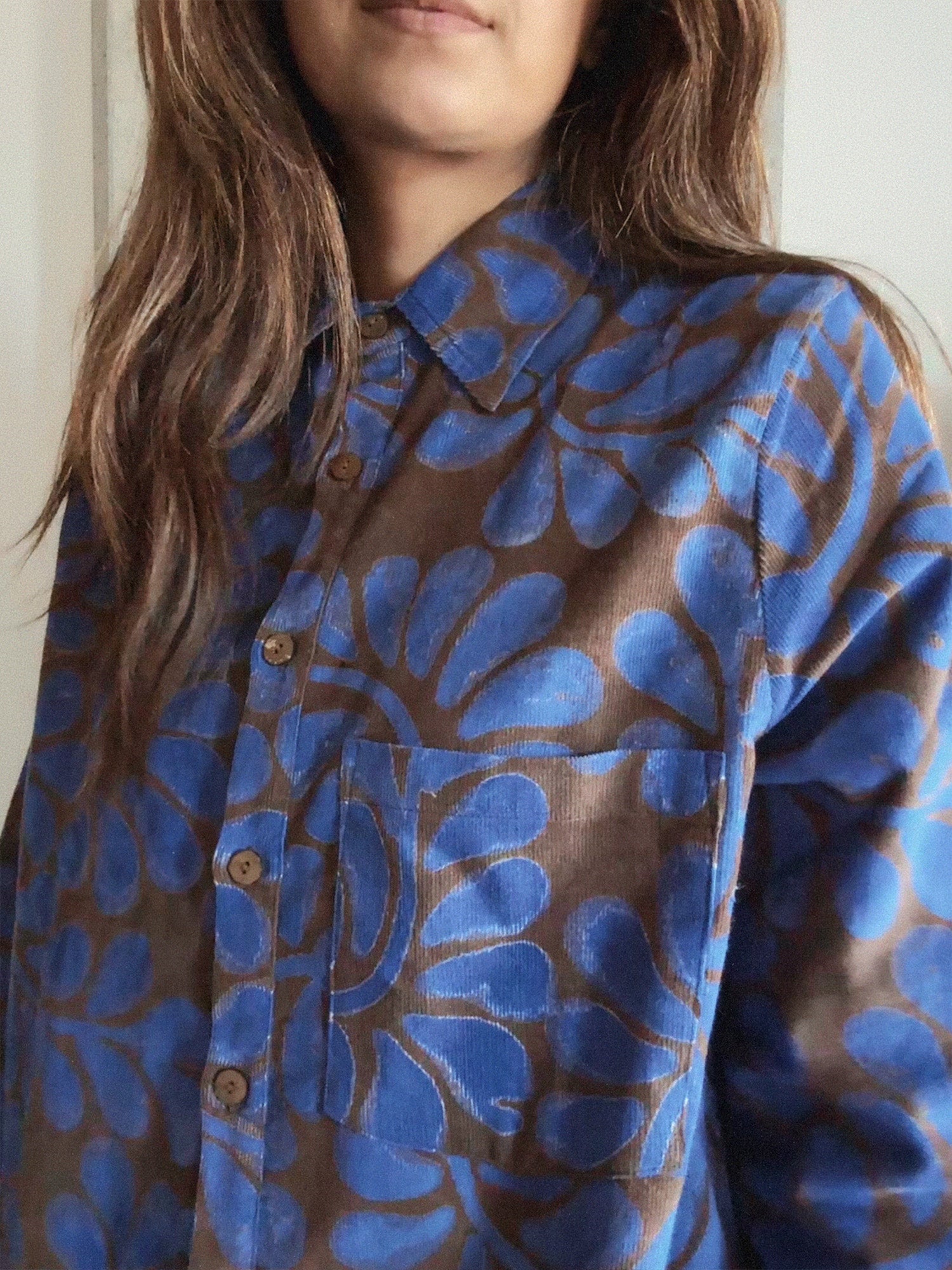 Person wearing a blue and brown floral patterned corduroy shirt