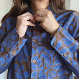 Person wearing a blue and brown patterned shirt with wooden buttons.