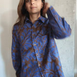 Person wearing a blue and brown floral patterned shirt against a neutral background