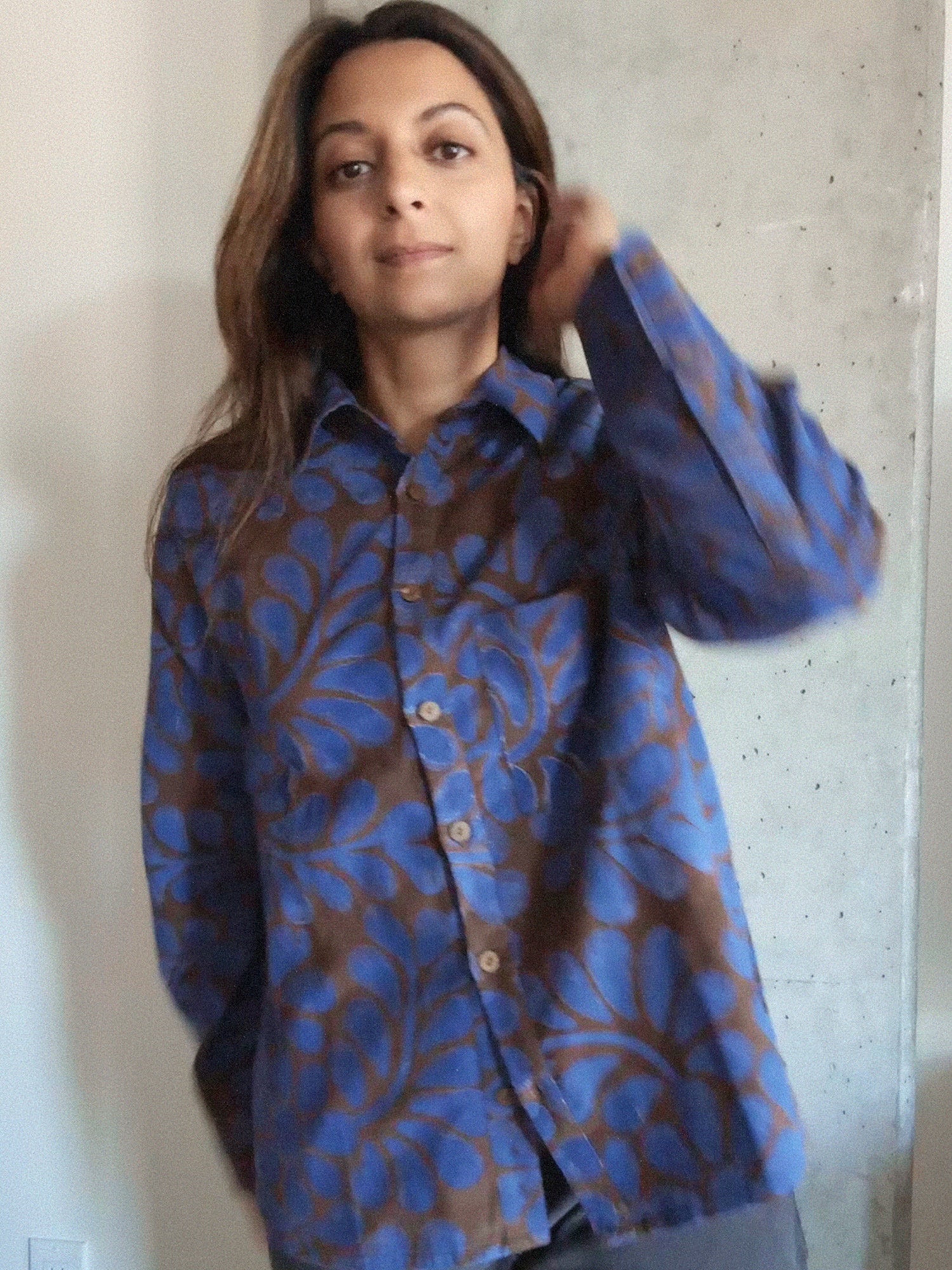 Person wearing a blue and brown floral patterned shirt against a neutral background