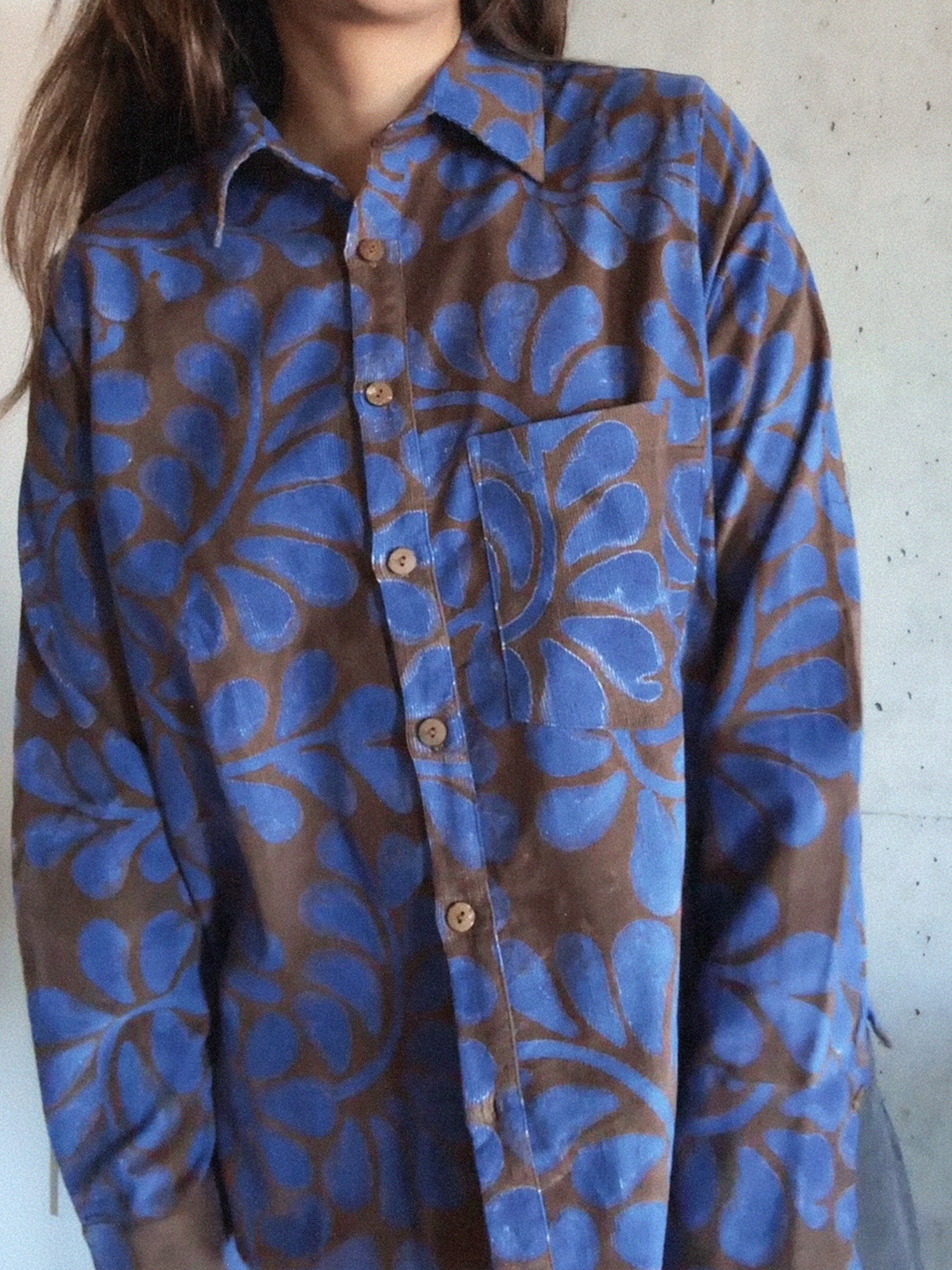 Blue and brown patterned shirt worn by a person against a plain background