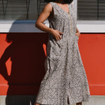 Person walking in front of a red and white building in a black and white floral print jumpsuit