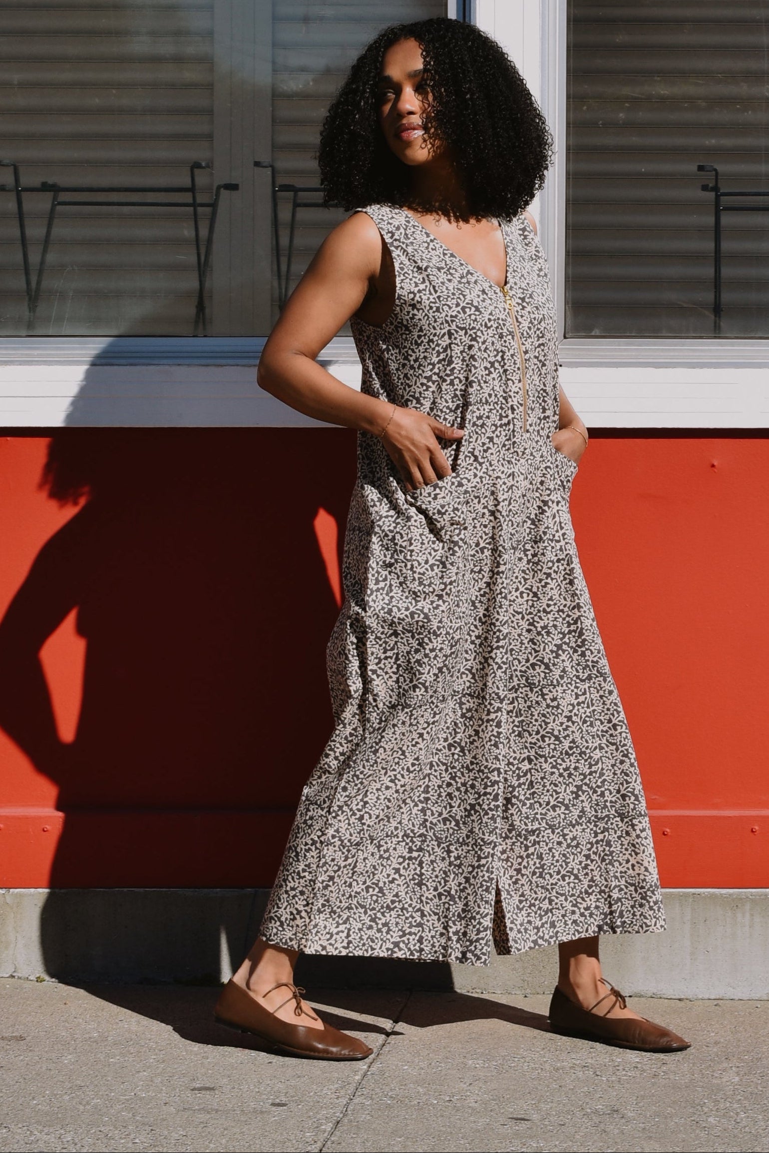 Person walking in front of a red and white building in a black and white floral print jumpsuit