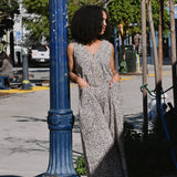 Woman in black and white floral print sleeveless jumpsuit standing against a lightpost