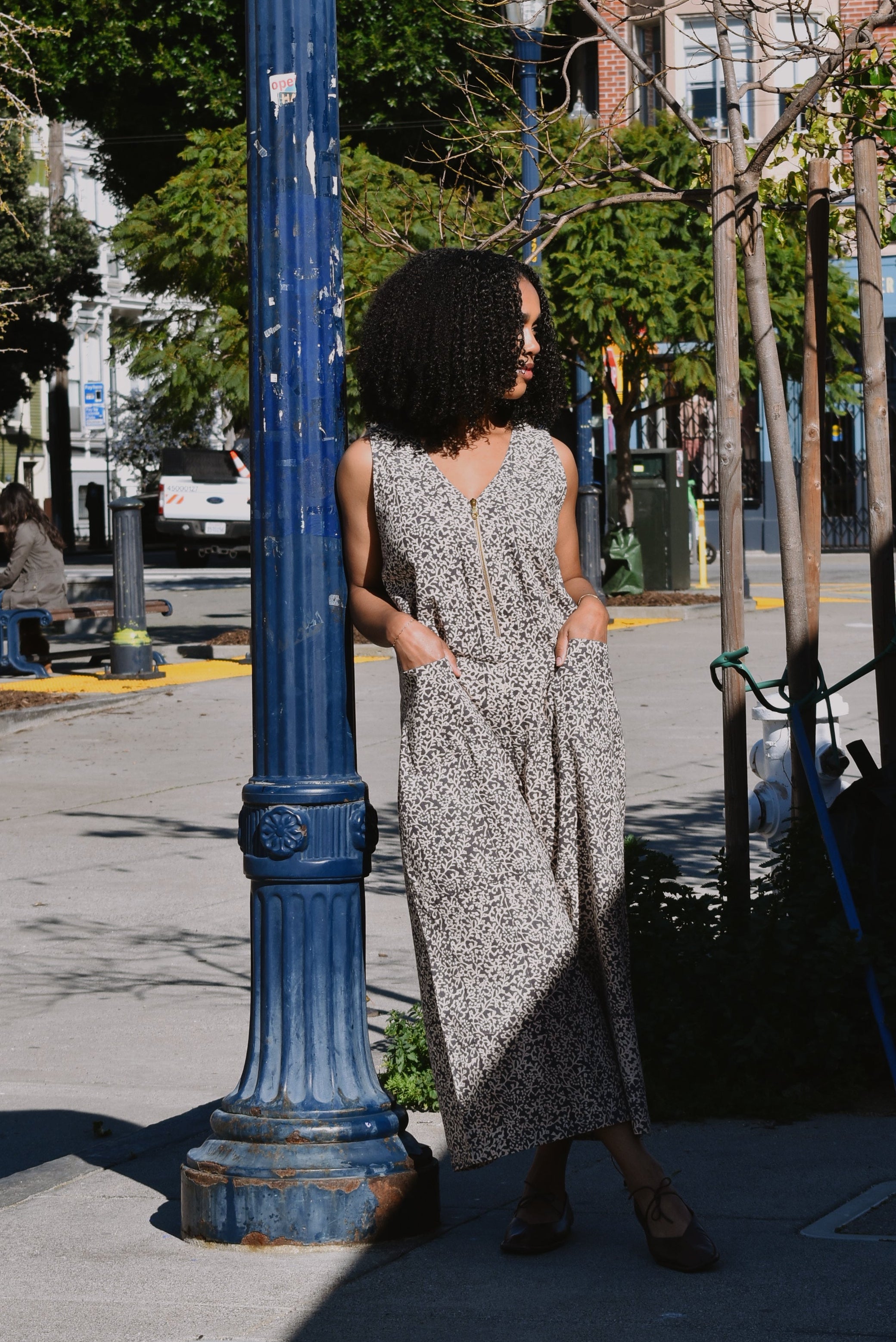 Woman in black and white floral print sleeveless jumpsuit standing against a lightpost