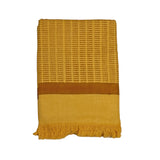 Block printed, yellow/brown, dash/line print bath towel, folded and laid flat against a white background