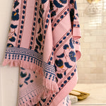 A pink bath towel with navy floral and geometric patterns, hanging in front of a shower