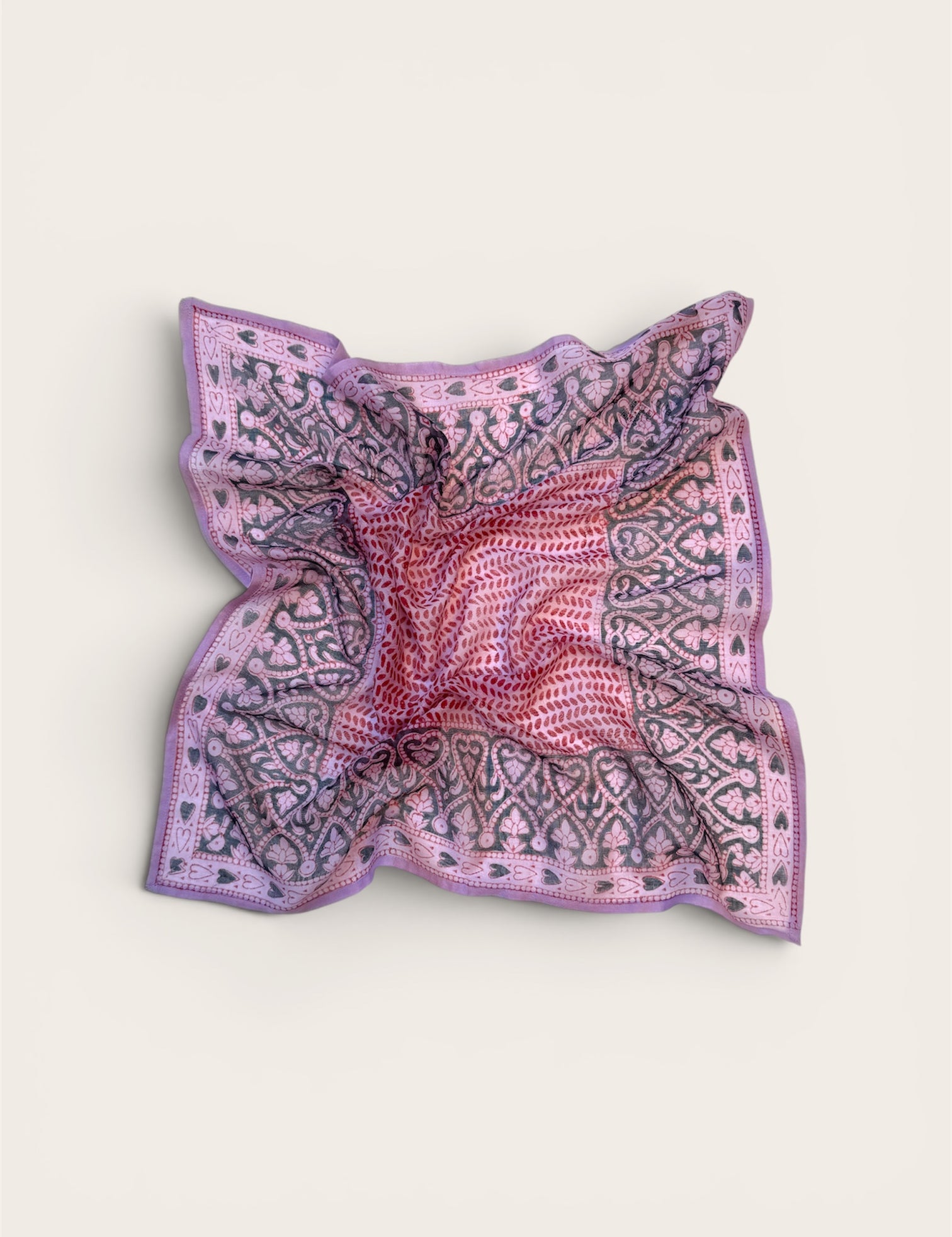 Pink and purple patterned bandana scarf on a light beige background