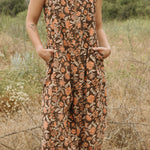 Close up of block printed floral printed Regina Corduroy Jumpsuit, hands in pockets, woman standing in a field