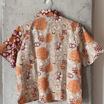 Short-sleeve shirt with a floral pattern hanging on a concrete wall.
