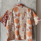 Short-sleeve shirt with a floral pattern hanging on a concrete wall.