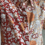 Close-up of a person wearing a patterned shirt with floral and abstract designs.