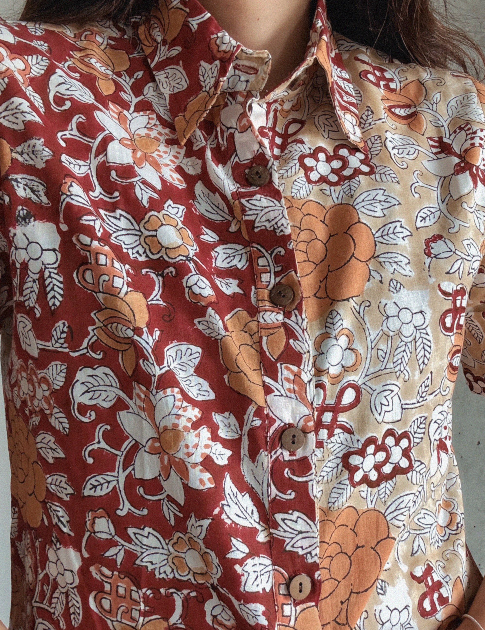 Close-up of a person wearing a patterned shirt with floral and abstract designs.