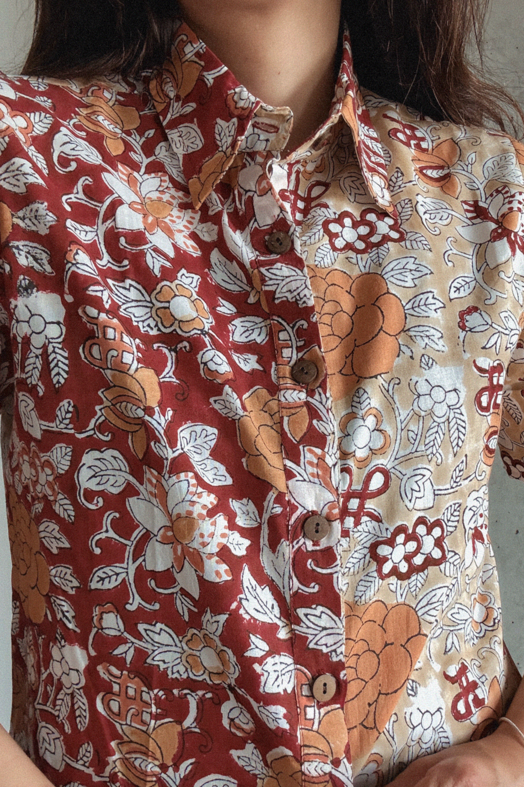 Close-up of a person wearing a patterned shirt with floral and abstract designs.