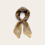 A square cotton scarf tied in a knot, featuring a gray and blue abstract pattern with fine blue lines, displayed on a light beige background.