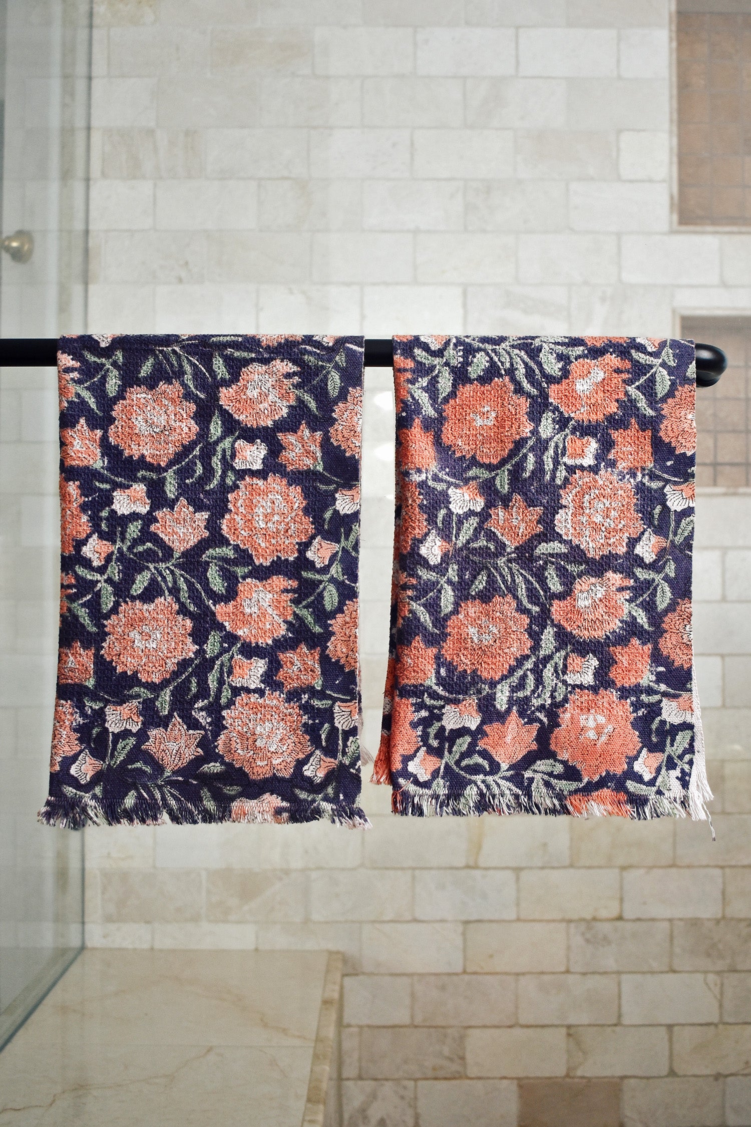 Block printed rose floral hand towels hanging on a shower rod