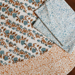 Orange and blue floral printed placemats and table napkins on a wooden table