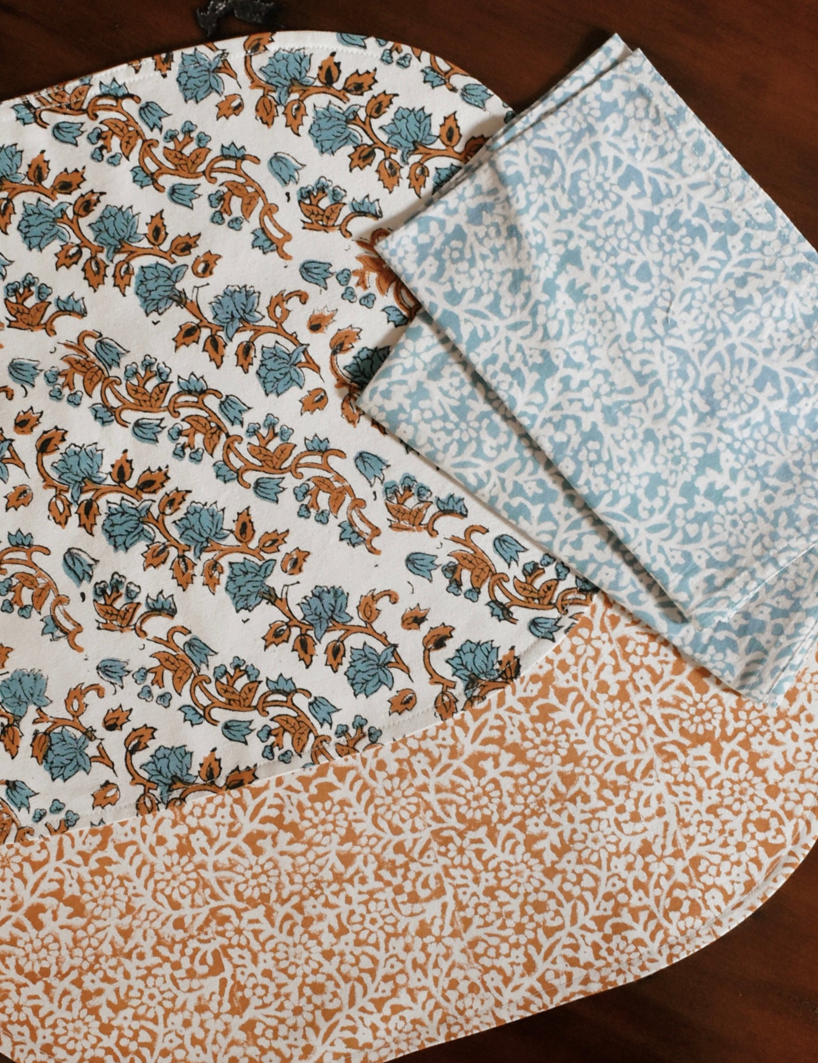 Orange and blue floral printed placemats and table napkins on a wooden table