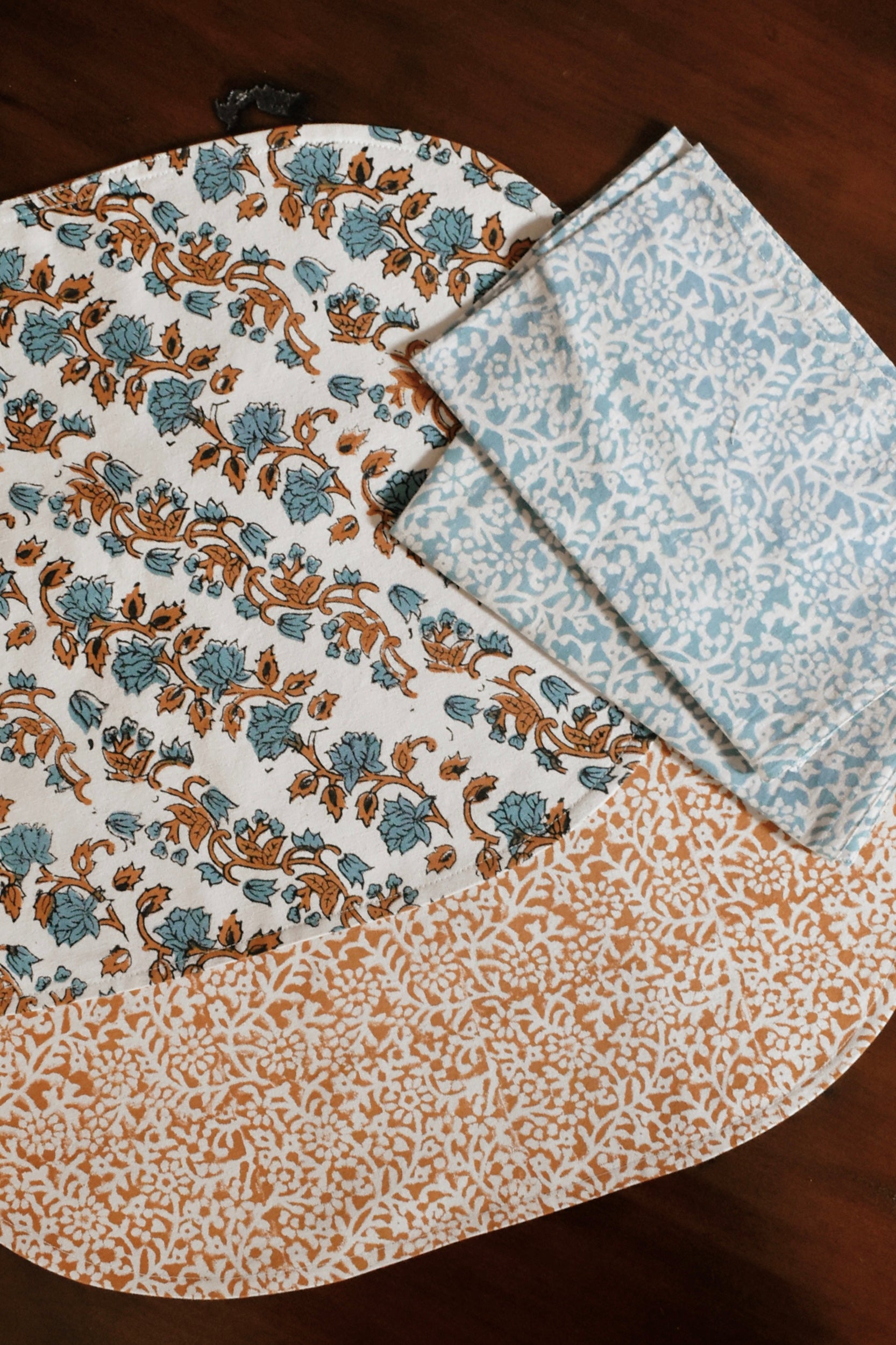 Orange and blue floral printed placemats and table napkins on a wooden table