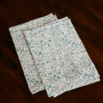 Two blue floral printed table napkins folded on wooden table