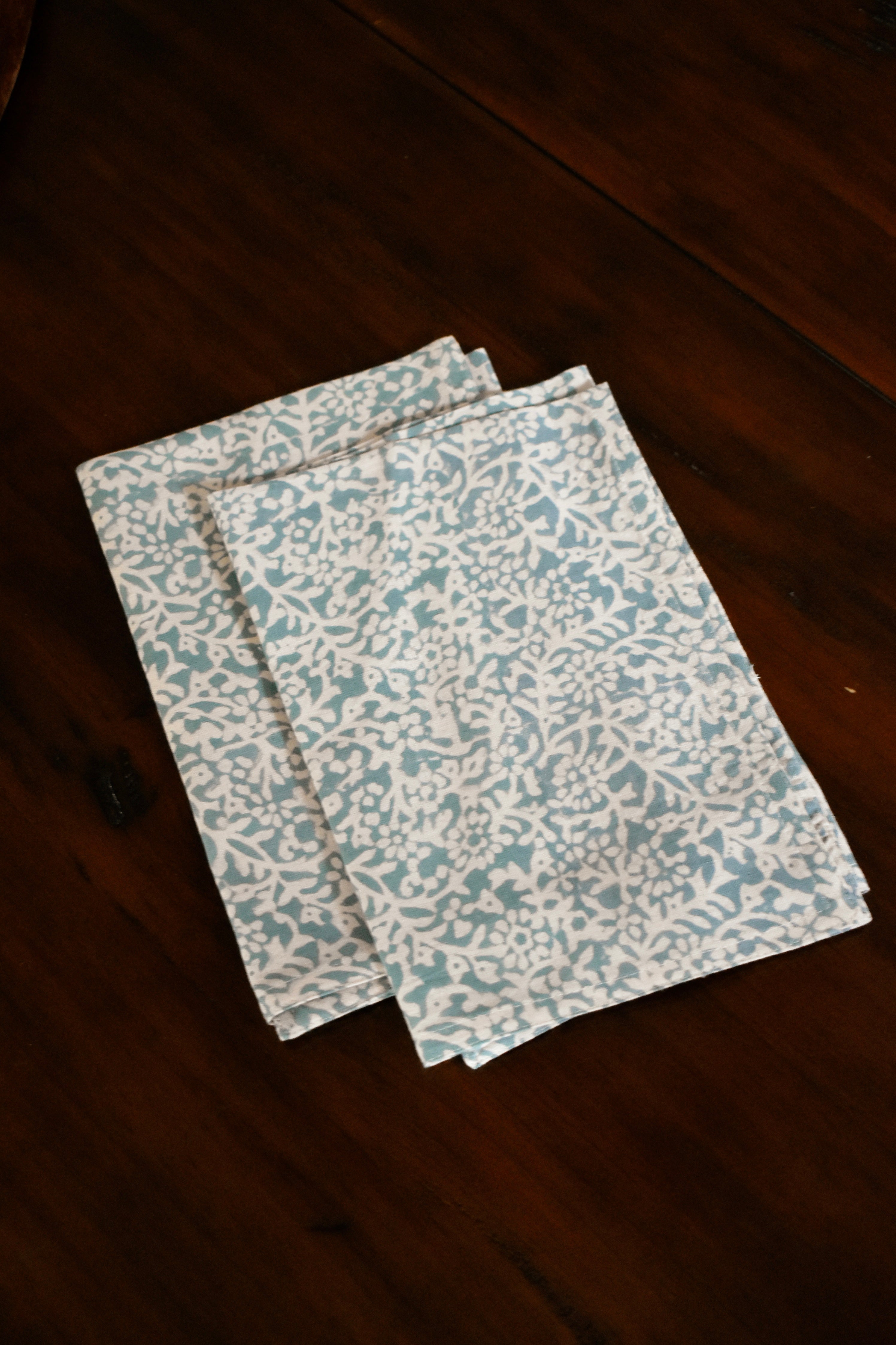 Two blue floral printed table napkins folded on wooden table