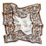 White scarf with brown floral print on a white background