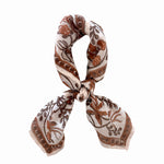 Patterned scarf with brown and beige floral design tied on a white background
