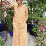 Woman wearing sleeveless yellow cotton jumpsuit near flowers and trees outside