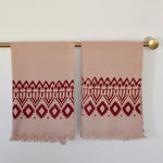 Block printed Terracotta hand towels, hanging on a golden rod. Towels have a geometric, diamond print. 