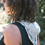 Woman wearing block print Mosaic bandana tied around neck against a black sleeveless dress. Back shot of the bandana draped down.