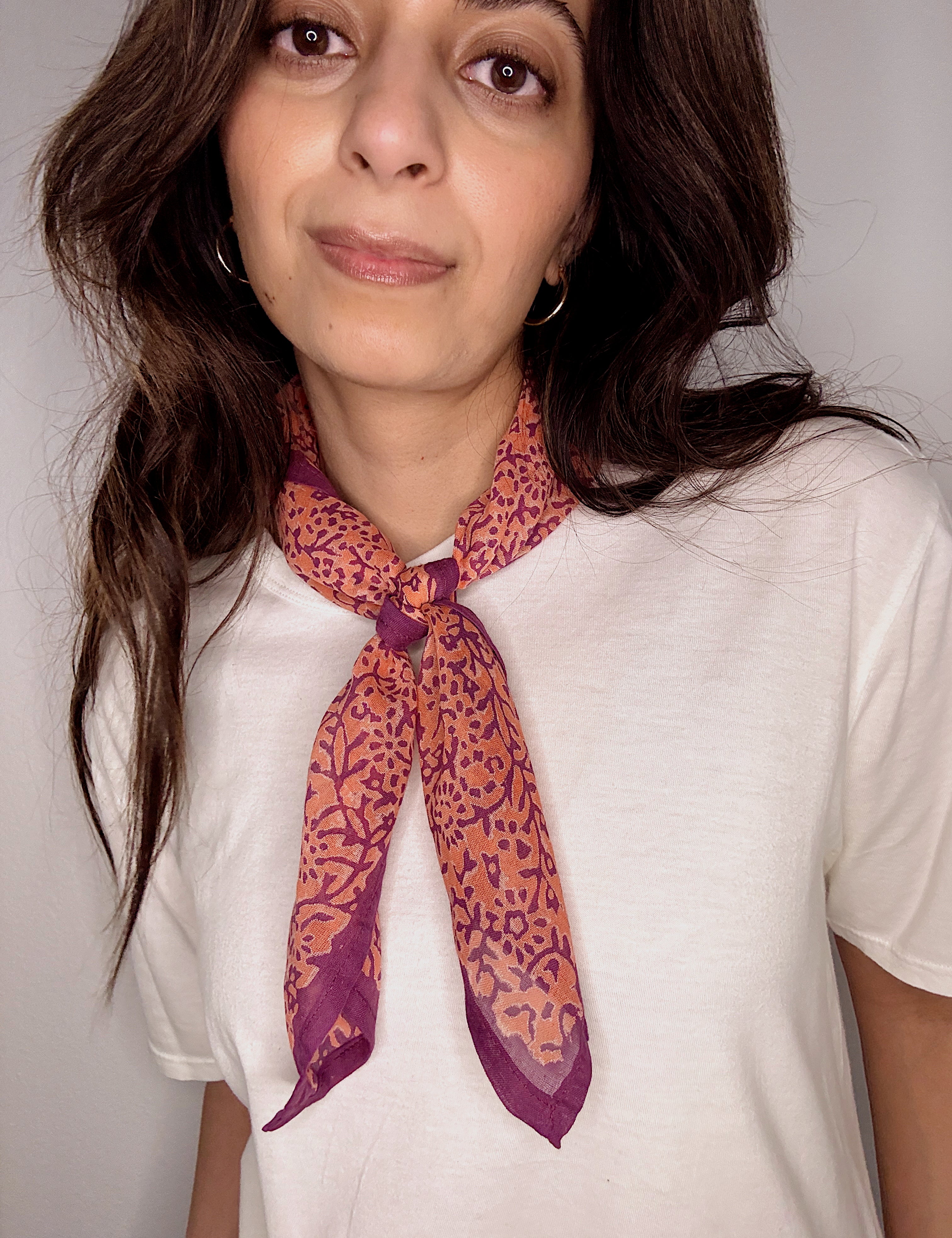 Woman wearing block printed Amber orange and purple bandana around the neck