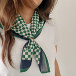 Person wearing a green and white checkered scarf on a plain background