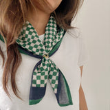 Person wearing a green and white checkered scarf on a plain background