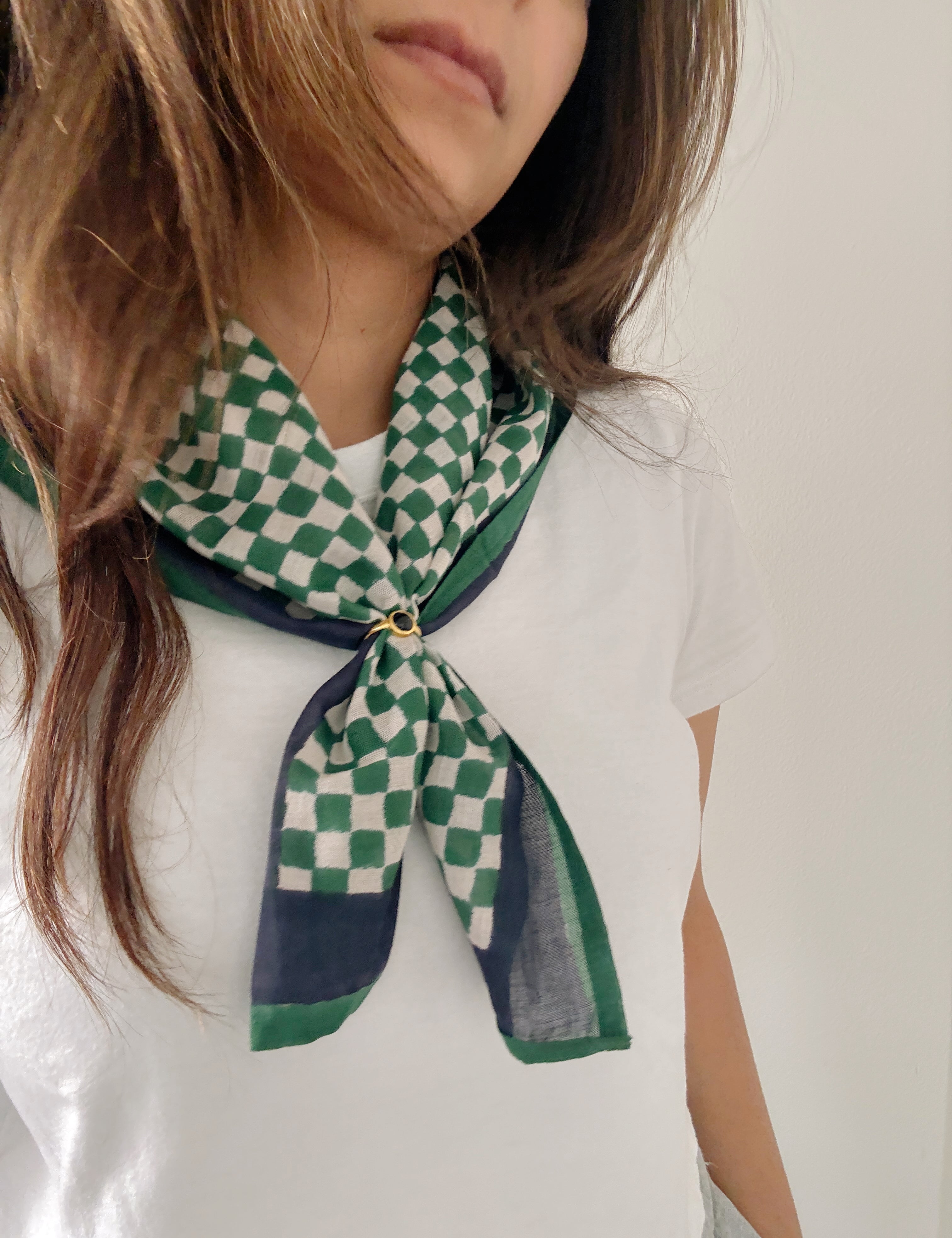 Person wearing a green and white checkered scarf on a plain background