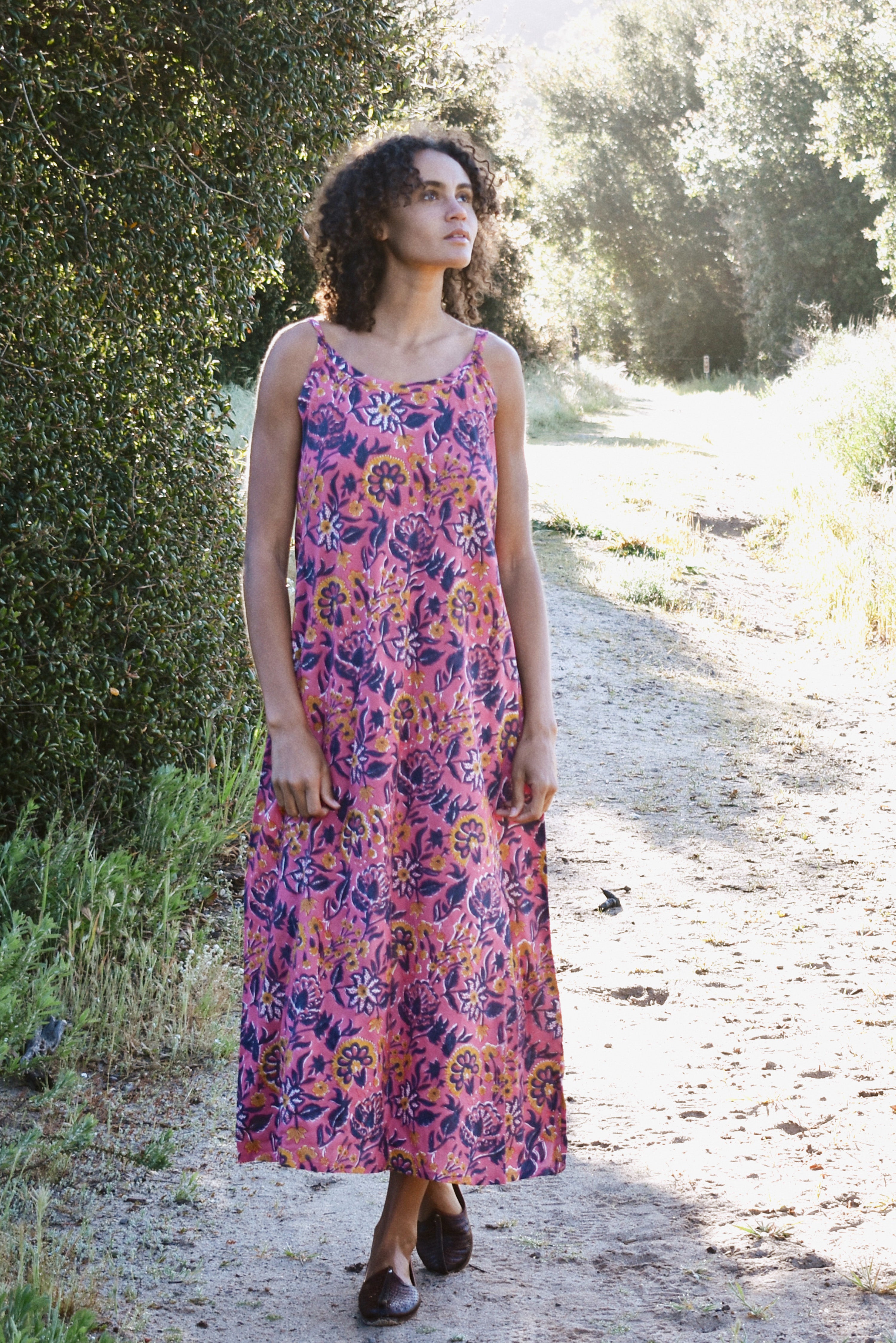 Woman wearing pink and purple floral printed strap maxi dress outside in nature