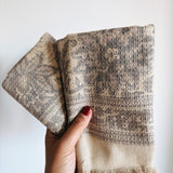 Hand holding textured beige and brown towels against a white background