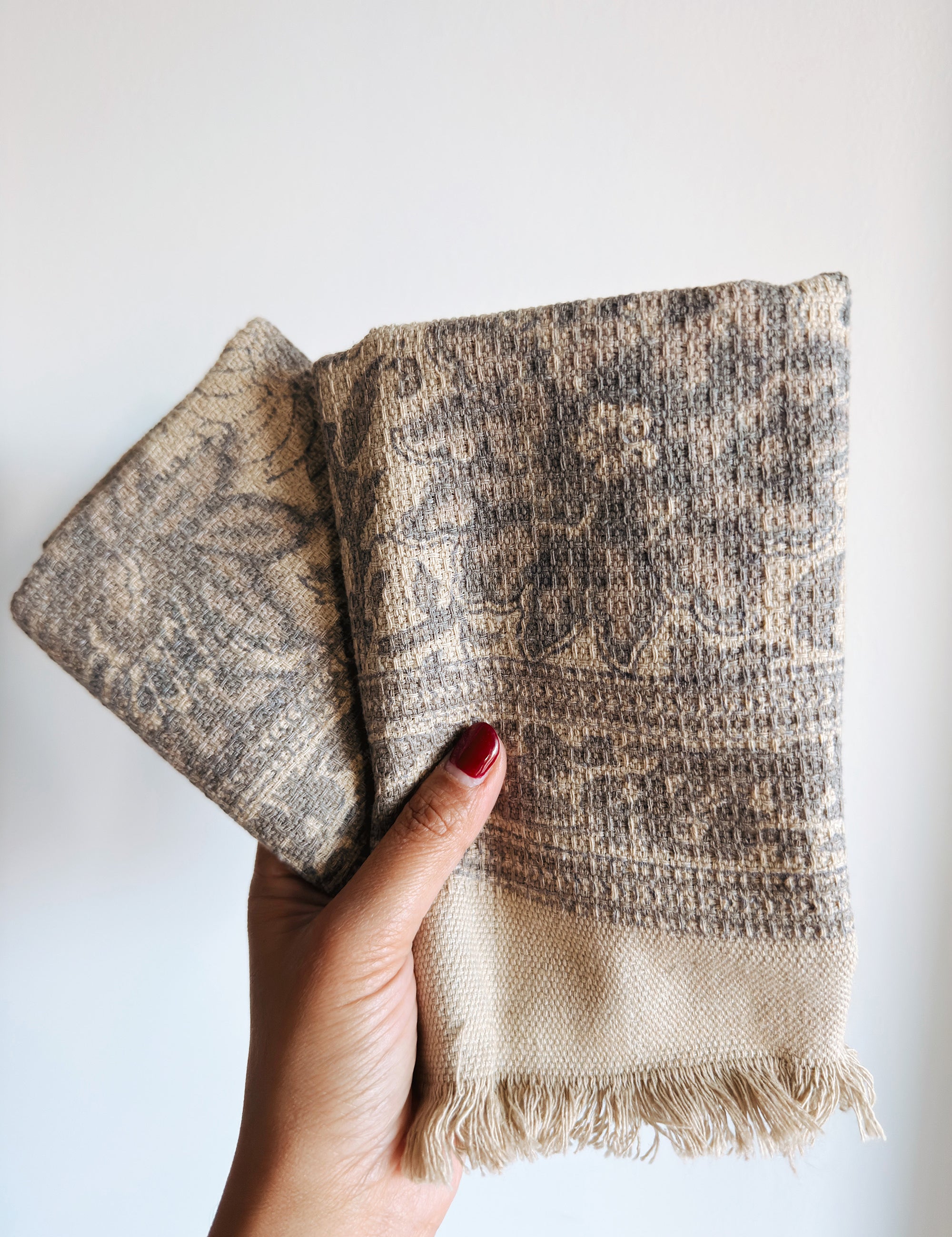 Hand holding textured beige and brown towels against a white background