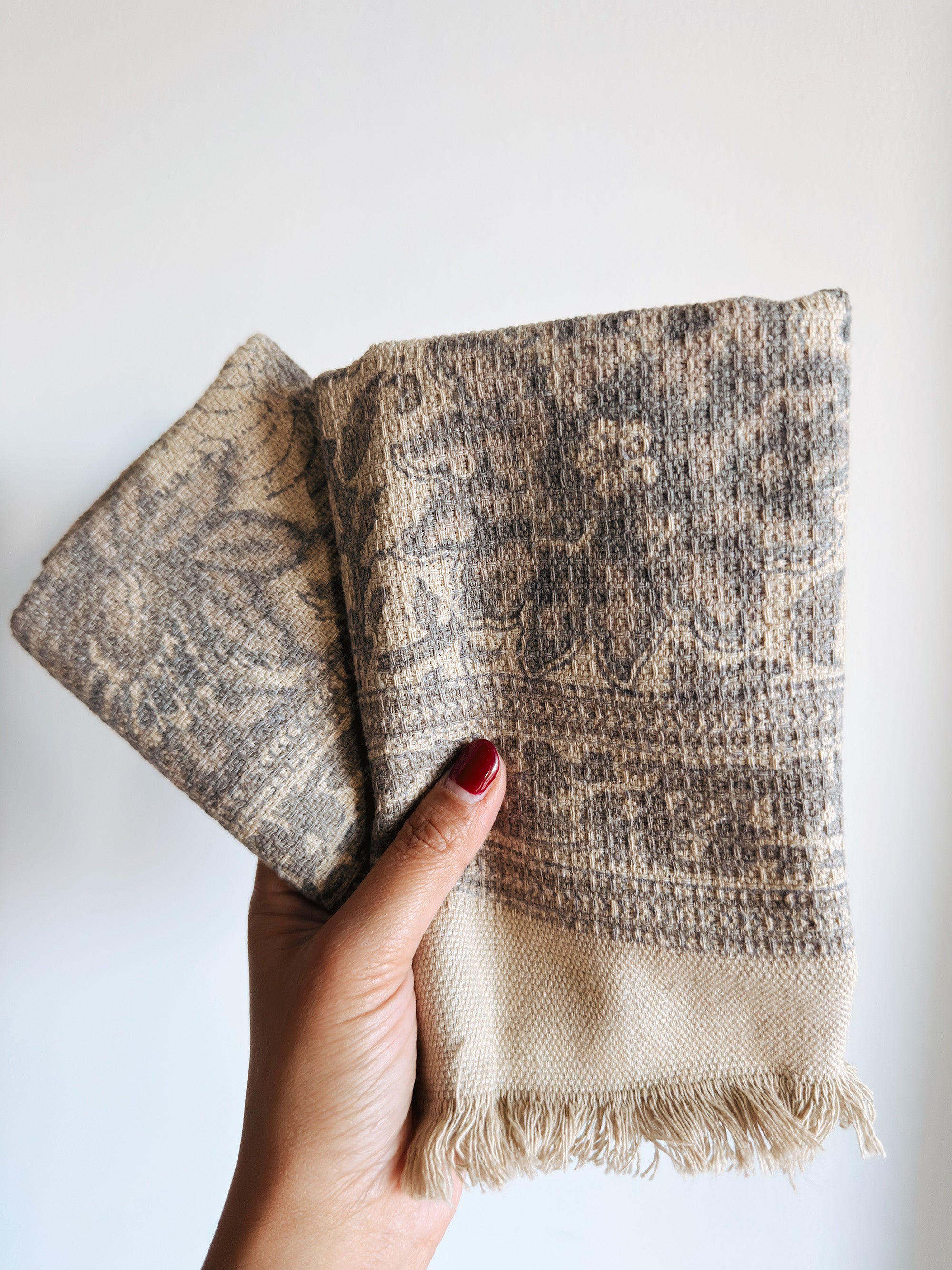 Hand holding textured beige and brown towels against a white background
