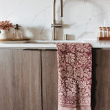 Kitchen with wooden cabinets, marble backsplash, and a patterned red and white towel hanging on the handle.