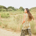 Woman wearing floral block printed sleeveless ruffle dress, back shot