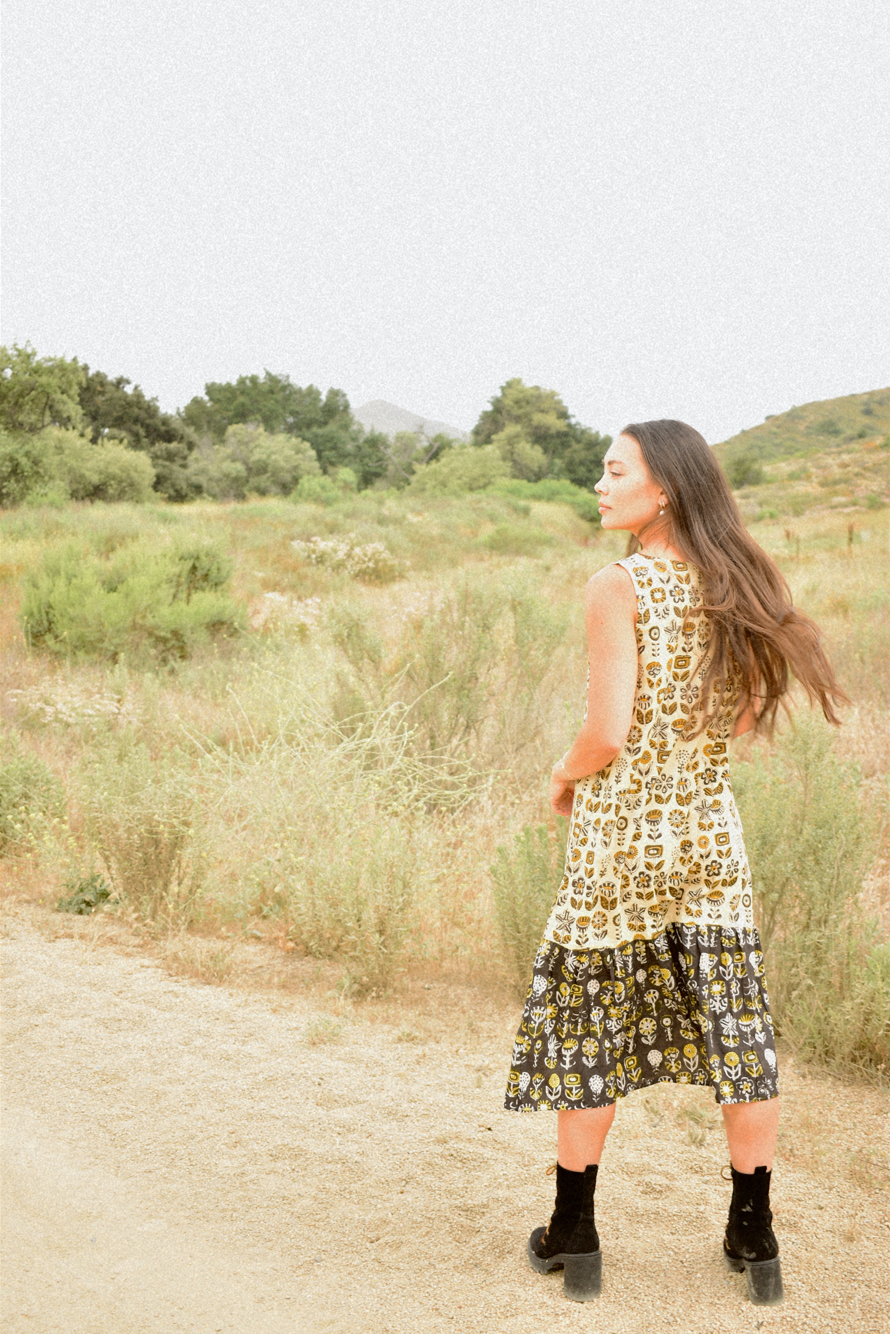 Woman wearing floral block printed sleeveless ruffle dress, back shot