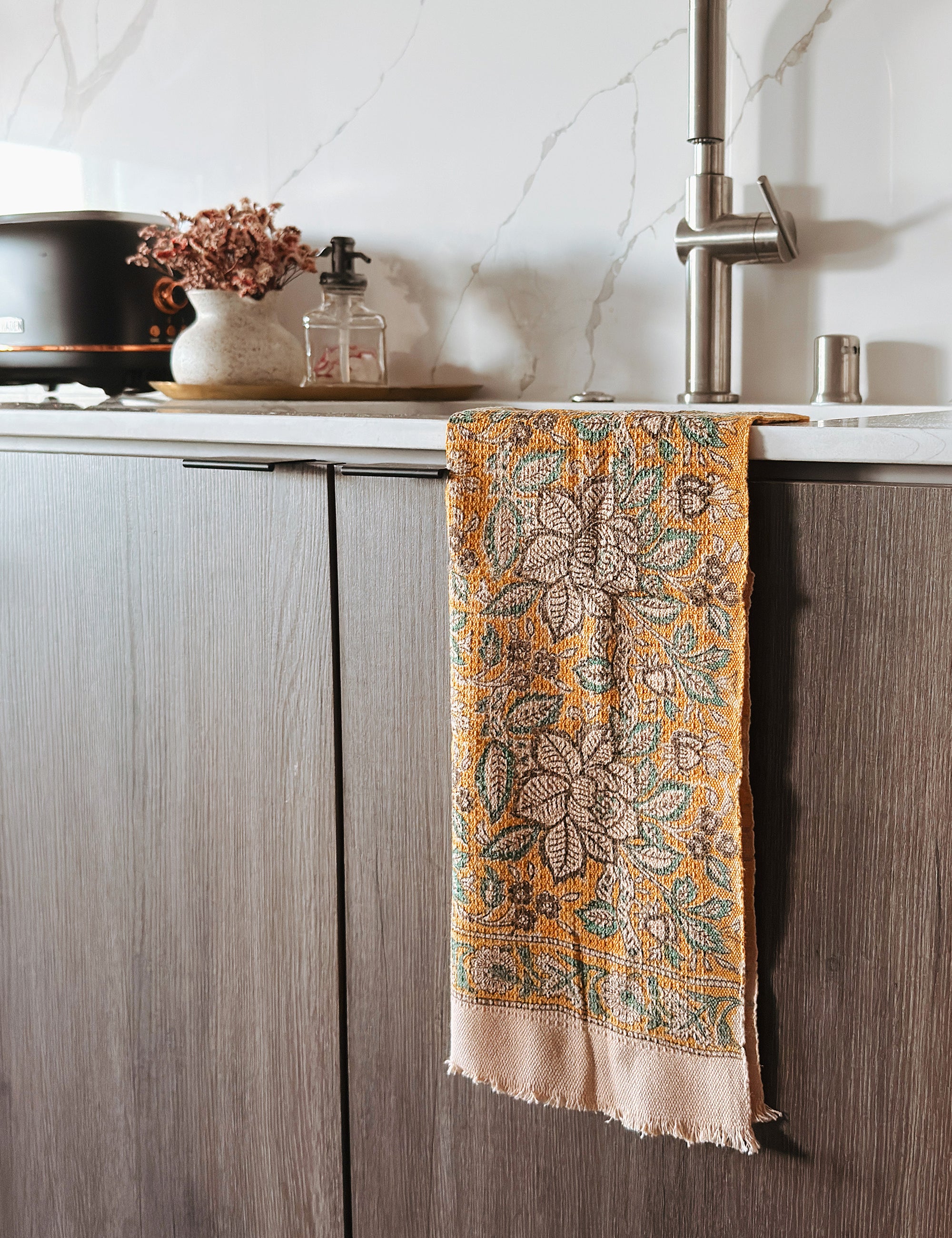 Decorative towel with floral pattern hanging on a kitchen cabinet