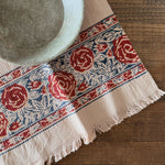 Decorative tablecloth with red floral pattern on a wooden surface