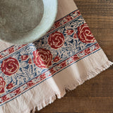 Decorative tablecloth with red floral pattern on a wooden surface