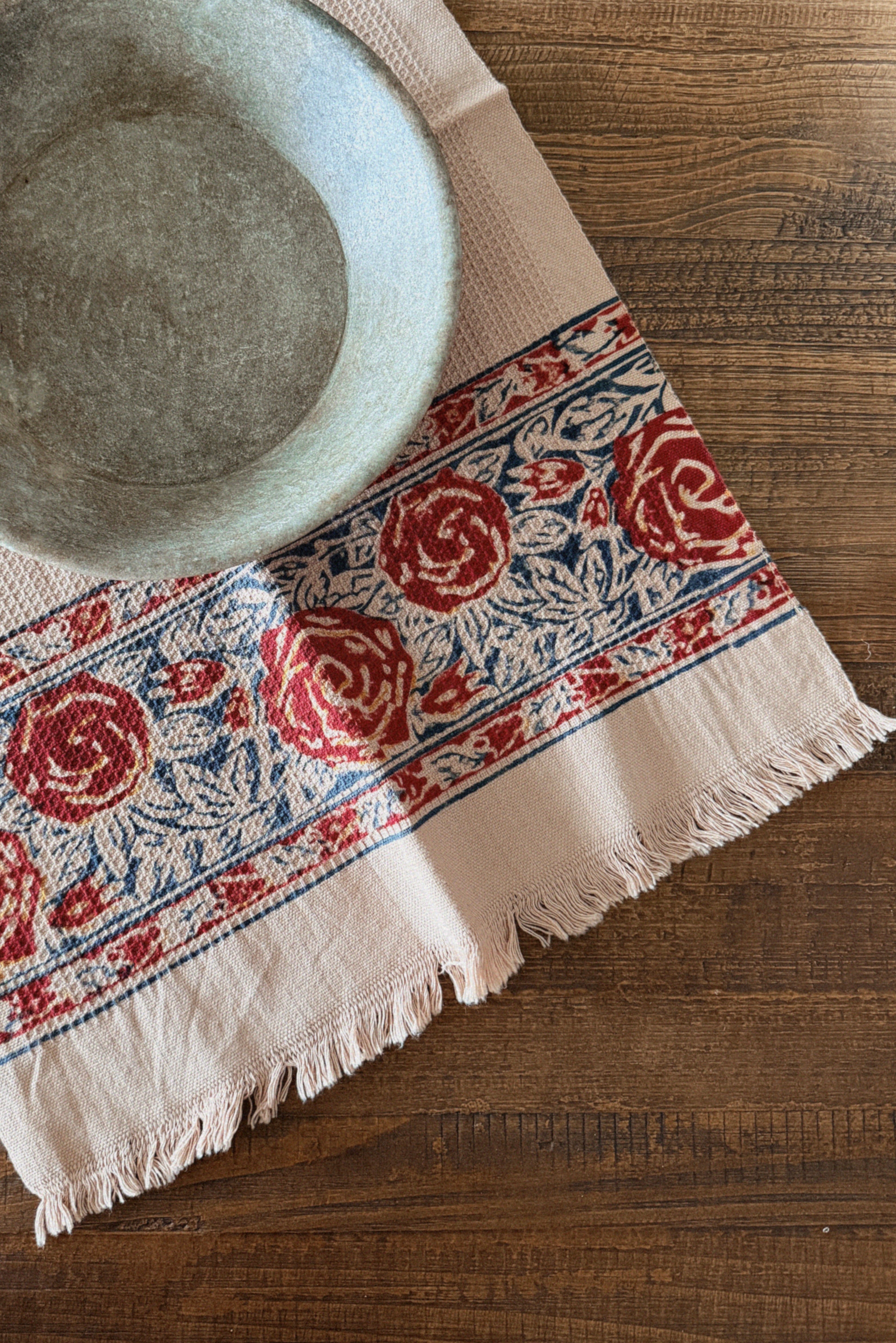Decorative tablecloth with red floral pattern on a wooden surface